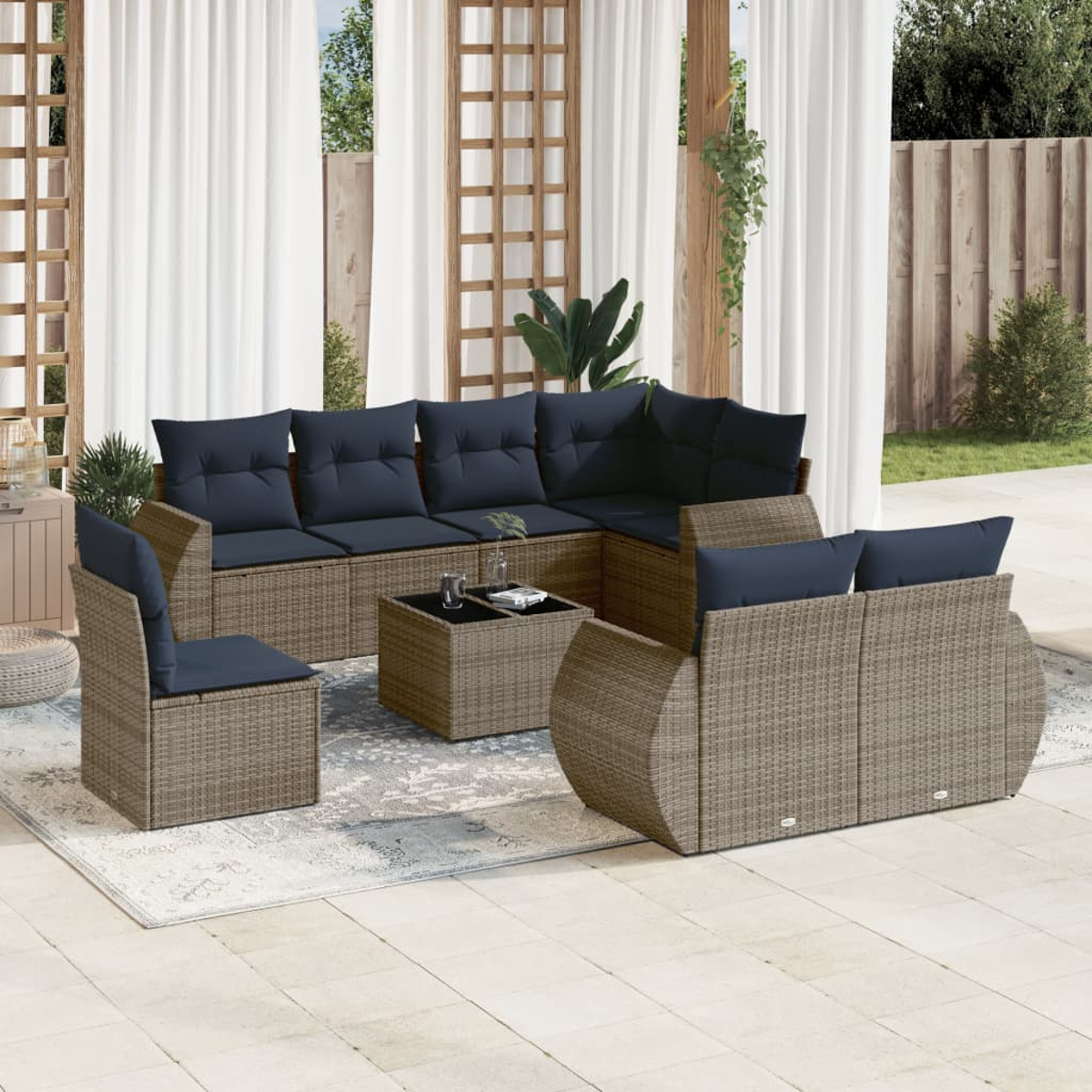 Terrassen-Set mit braunen Korbmöbeln und marineblauen Kissen. Enthält Sofa, Stühle und einen Couchtisch auf einem Teppich.