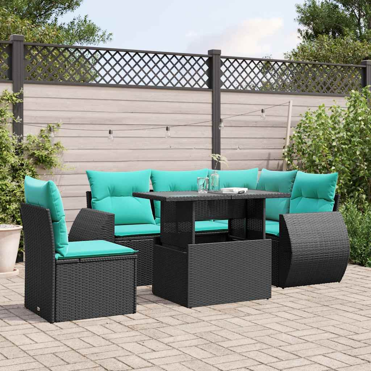 Garten-Terrassenset mit schwarzen Korbmöbeln und türkisfarbenen Kissen. Ein Tisch steht in der Mitte vor einem Holzzaun.