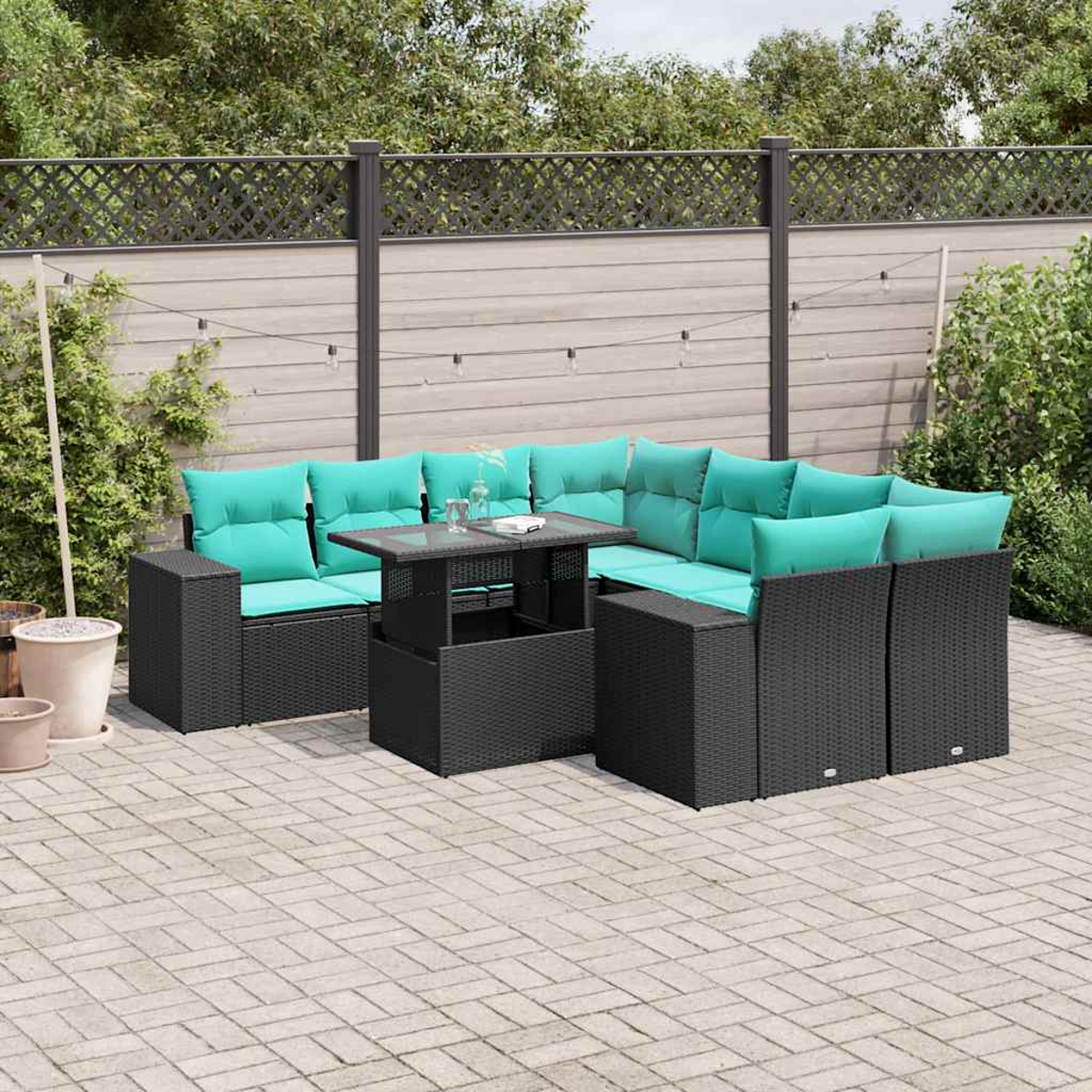 Outdoor-Ecksofa mit türkisfarbenen Kissen und einem quadratischen Tisch auf einer Terrasse. Im Hintergrund ein Holzzaun und Grün.