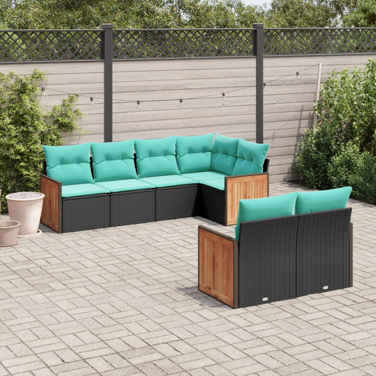 Gartenmöbel-Set. Enthält ein Ecksofa und eine kleinere Zweisitzer-Couch, beide mit türkisfarbenen Kissen. Auf einer gepflasterten Terrasse.