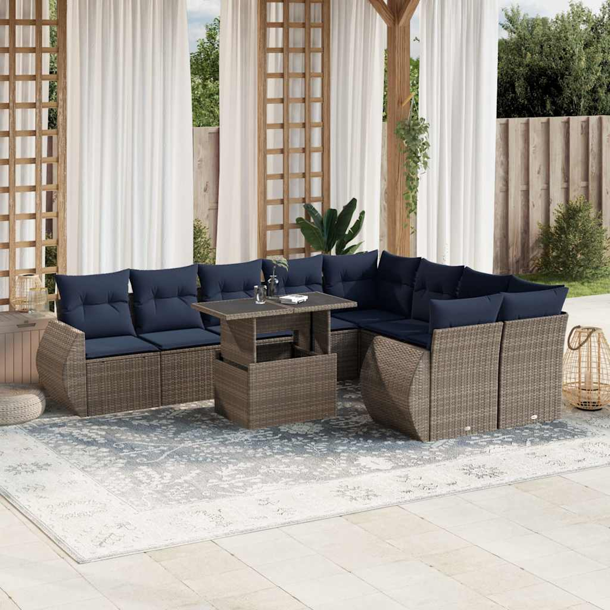 Outdoor-Ecksofa mit blauen Kissen und einem Tisch mit Hubfunktion. Auf einem gemusterten Teppich, mit Vorhängen und Grün im Hintergrund.