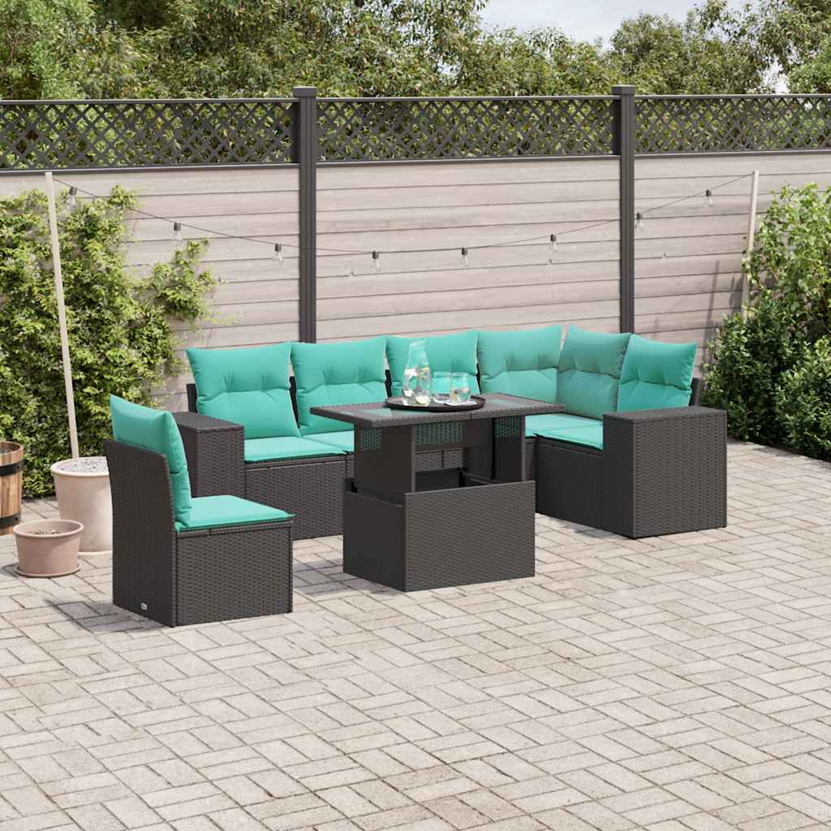Gartenmöbel-Set: dunkelgraues Korbgeflecht mit türkisfarbenen Kissen. Inklusive Tisch und Ecksofa auf einer Terrasse. Holzzaun im Hintergrund.