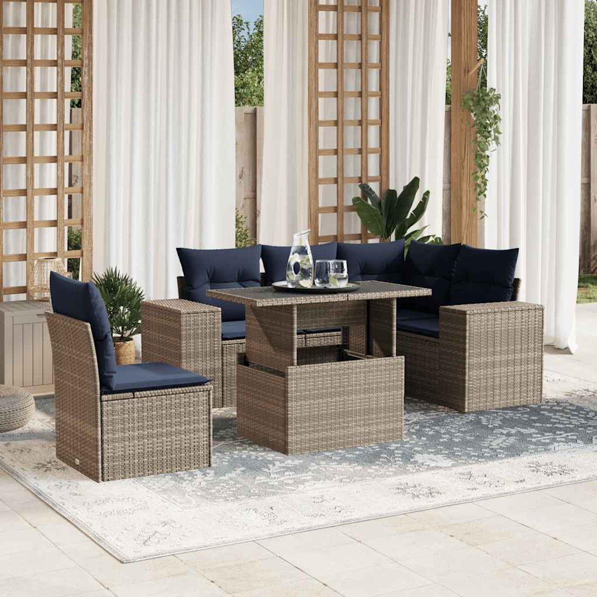 Outdoor-Terrassenset mit braunen Korbmöbeln, marineblauen Kissen und einem Tisch mit Glasplatte auf einem gemusterten Teppich, weiße Vorhänge im Hintergrund.