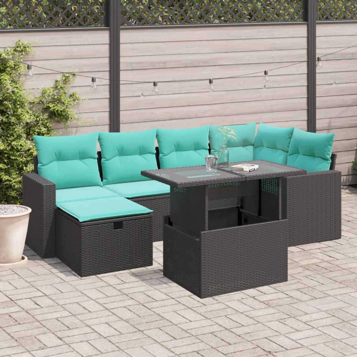 Outdoor-Ecksofa mit türkisfarbenen Kissen. Vorne steht ein Tisch mit hebbarer Platte. Im Hintergrund ein Holzzaun.