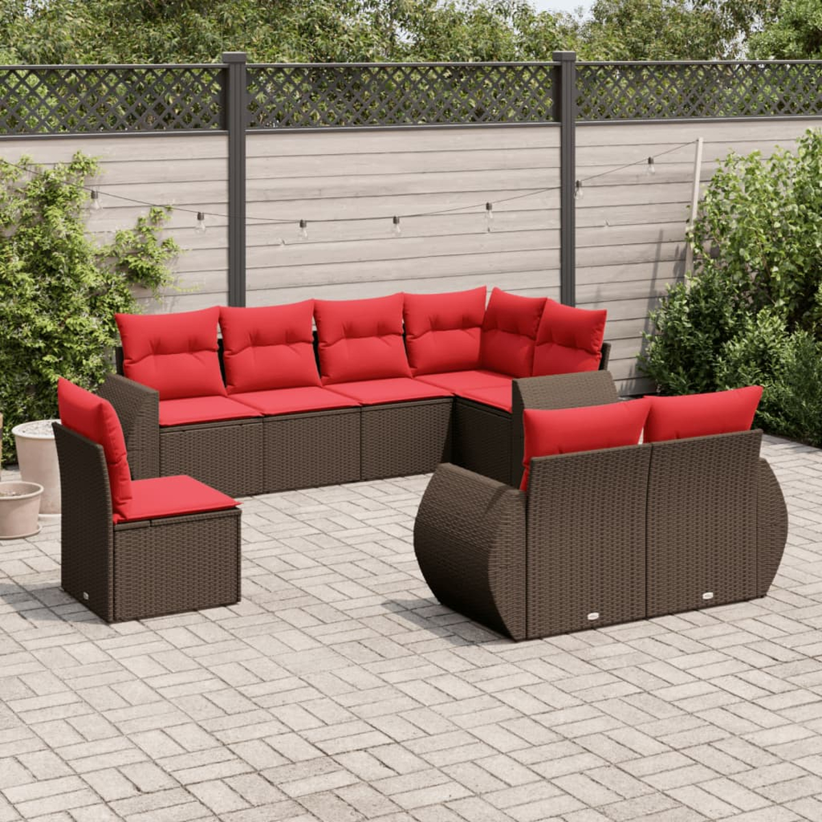 Gartenmöbel-Set aus Korbgeflecht mit roten Kissen auf einer Terrasse. Das Set umfasst ein Ecksofa, eine Couch und einen Stuhl.