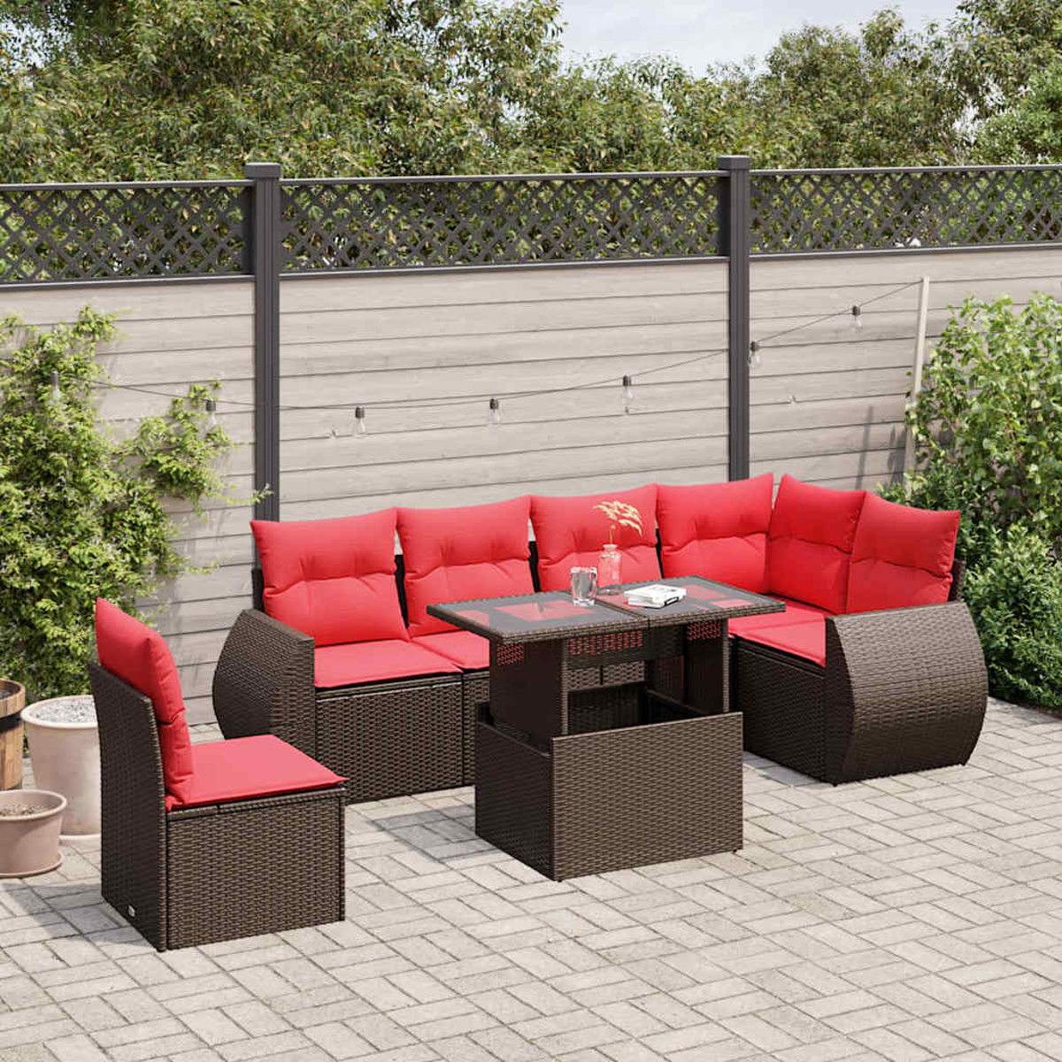 Garten-Set mit roten Kissen, einem Tisch mit Glasplatte und einem braunen Korbgewebe-Rahmen, auf einer Backstein-Terrasse.