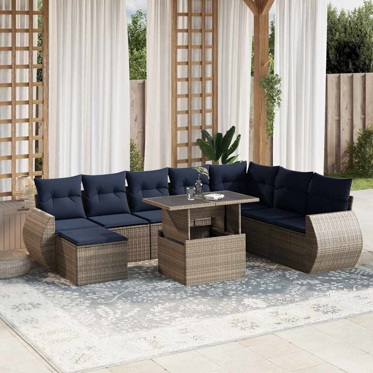 Outdoor-Sitzgruppe mit blauen Kissen. Enthält einen Tisch und einen gemusterten Teppich. Im Hintergrund weiße Vorhänge und Holzstrukturen.