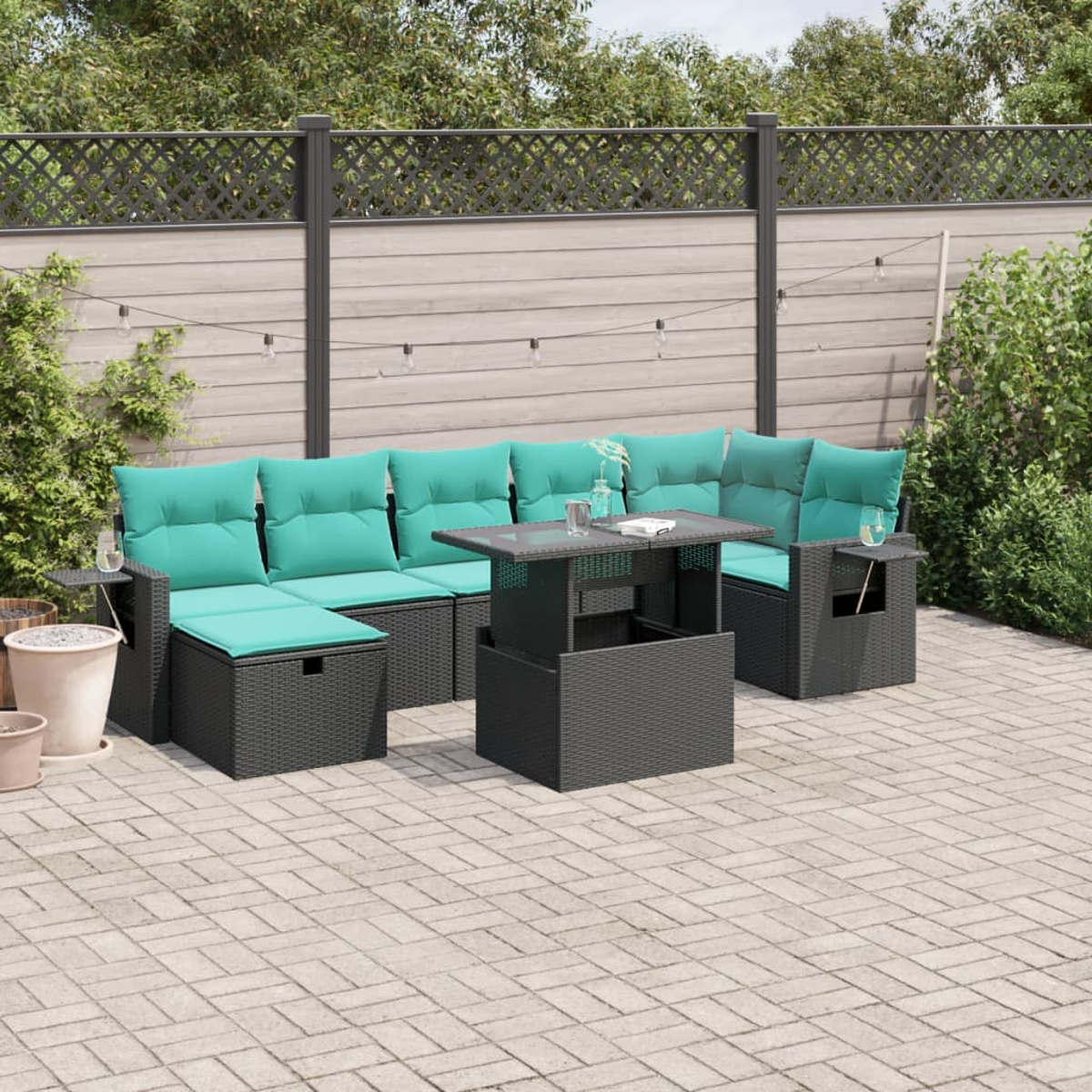 Outdoor-Terrassenset mit türkisfarbenen Kissen, einem Couchtisch und Beistelltischen. Das Set steht auf einer Ziegelterrasse, mit Zaun und Grün im Hintergrund.