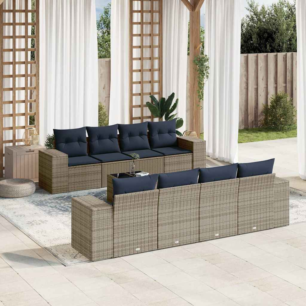 Terrassenmöbel: Korbsessel mit marineblauen Kissen auf einer Terrasse. Weiße Vorhänge und Grün im Hintergrund, mit Holzkonstruktion.