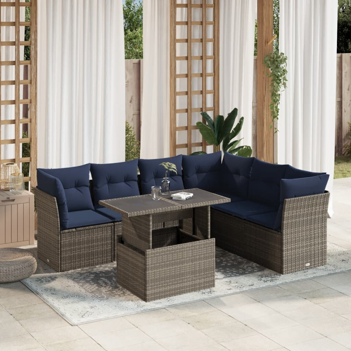 Outdoor-Sofa aus Korbgeflecht mit blauen Kissen und einem Tisch mit Hubfunktion. Die Szene umfasst Vorhänge und Grün.