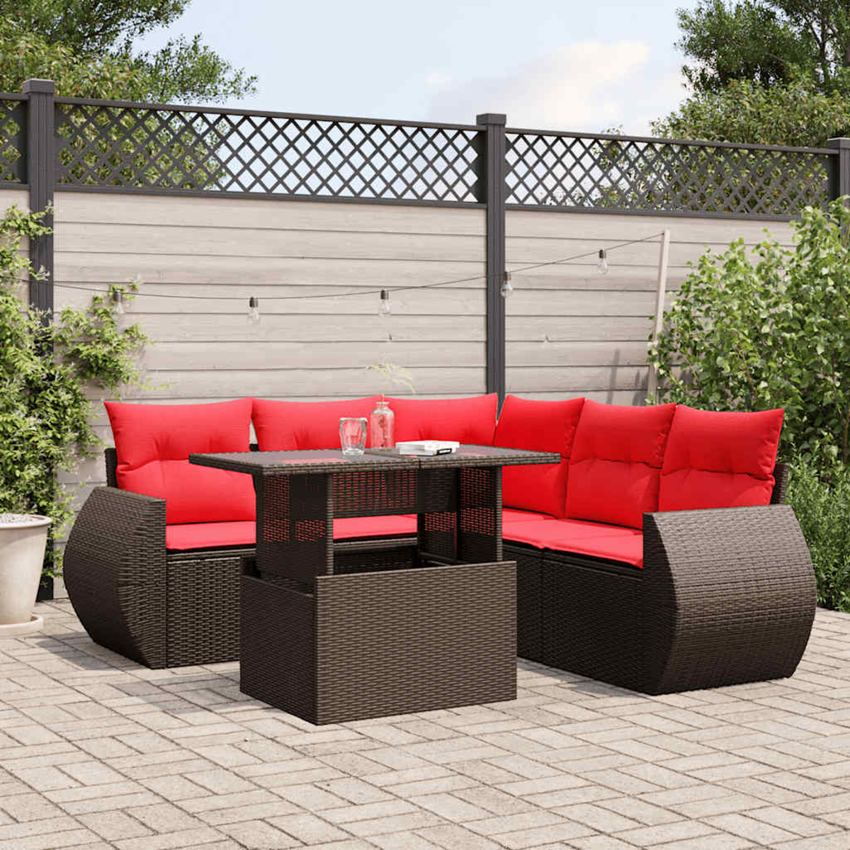 Gartenmöbel-Set mit roten Kissen, einem braunen Tisch und einem Zaun im Hintergrund.