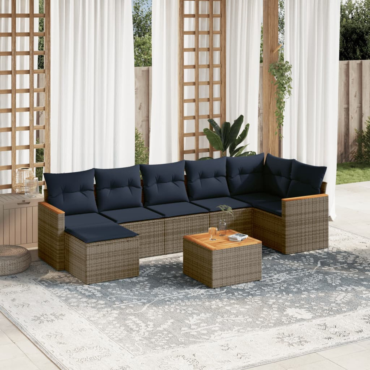Outdoor-Ecksofa mit marinefarbenen Kissen und einem Holztisch auf einem gemusterten Teppich. Vorhänge und Holzgitter im Hintergrund.