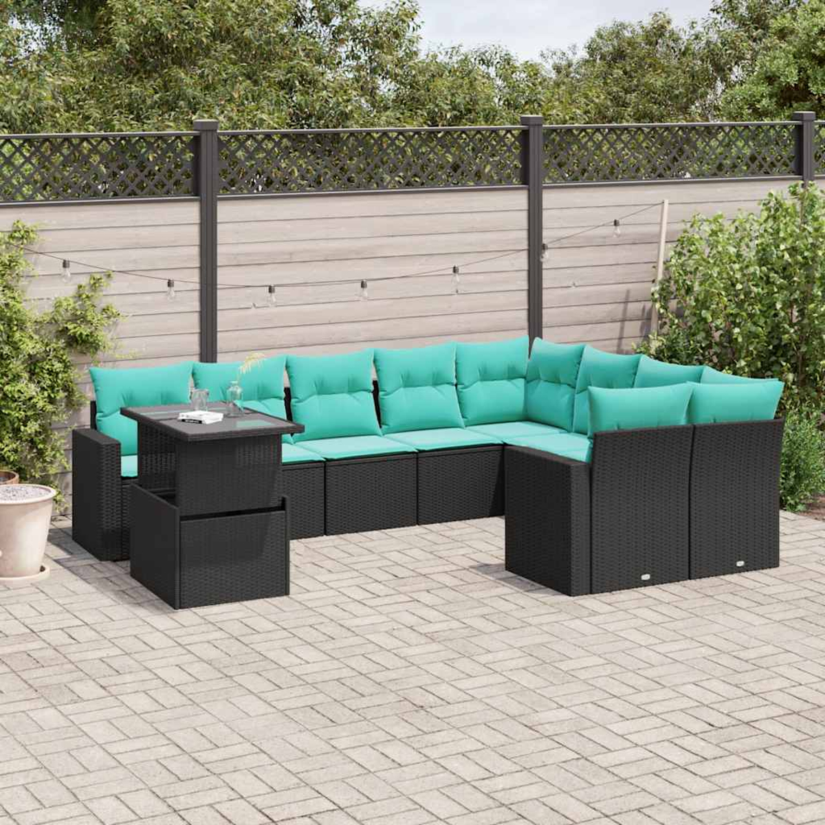 Outdoor-Ecksofa mit türkisfarbenen Kissen und schwarzem Korbgewebe. Ein kleiner Tisch ist in der Nähe. Die Szene ist eine Terrasse mit Zaun.