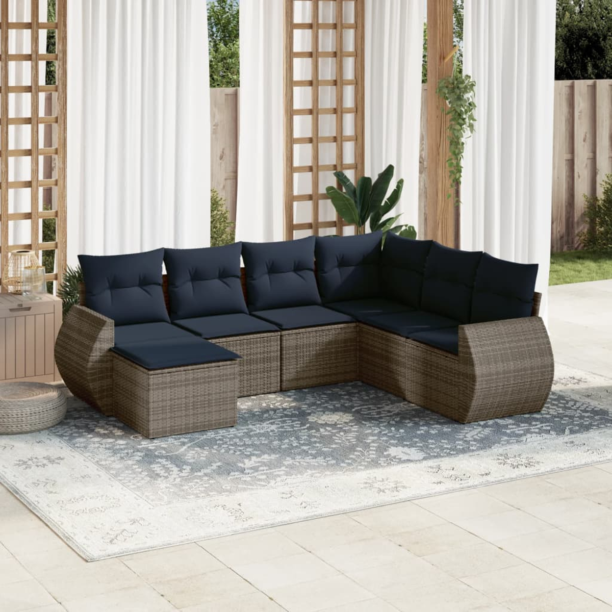 Outdoor-Ecksofa mit marineblauen Kissen auf einem gemusterten Teppich. Weiße Vorhänge und Holzgitter im Hintergrund, die eine Terrasse bilden.