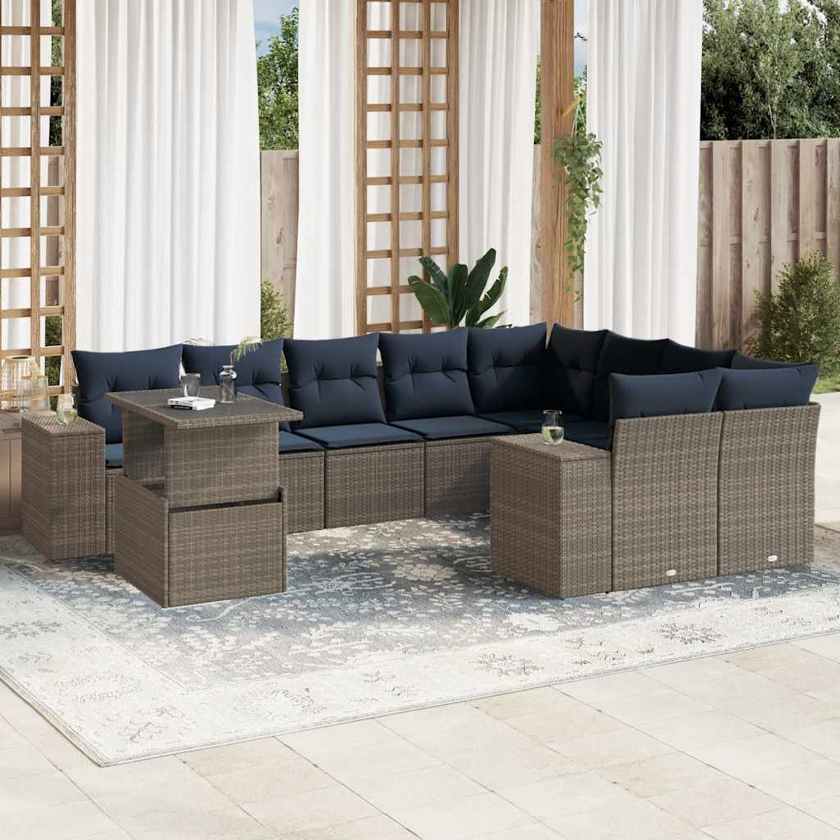 Outdoor-Ecksofa mit marineblauen Kissen, zwei Beistelltischen und einem gemusterten Teppich auf einer Terrasse mit weißen Vorhängen.