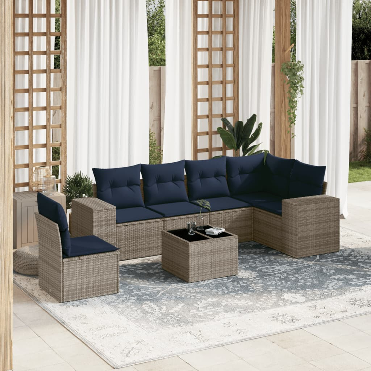 Outdoor-Sitzbereich mit Ecksofa, Stuhl und Couchtisch auf einem gemusterten Teppich, weiße Vorhänge im Hintergrund.