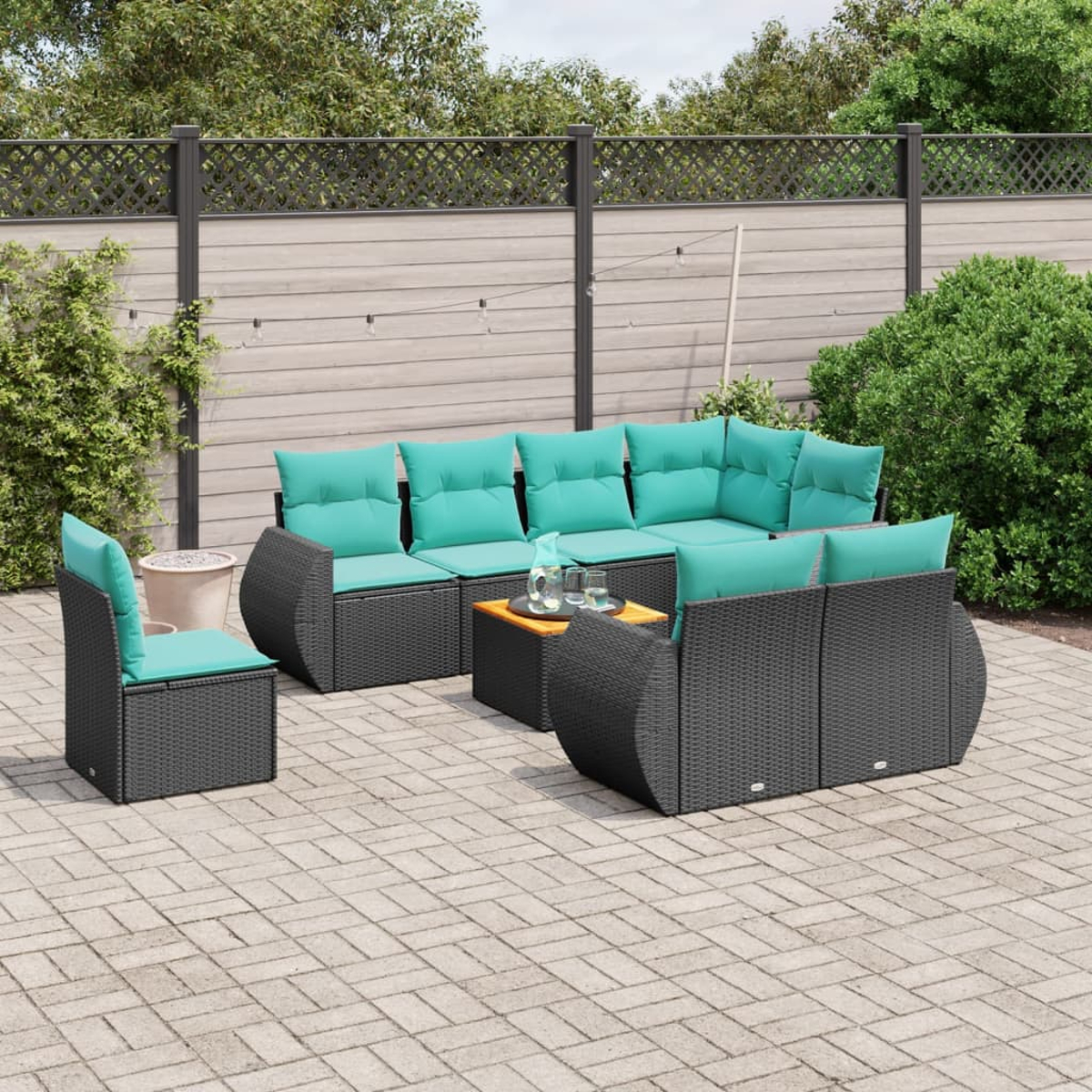 Gartenmöbel-Set mit tealfarbenen Kissen. Beinhaltet Sofa, Stühle und Couchtisch, auf einer Backstein-Terrasse mit Zaun im Hintergrund.
