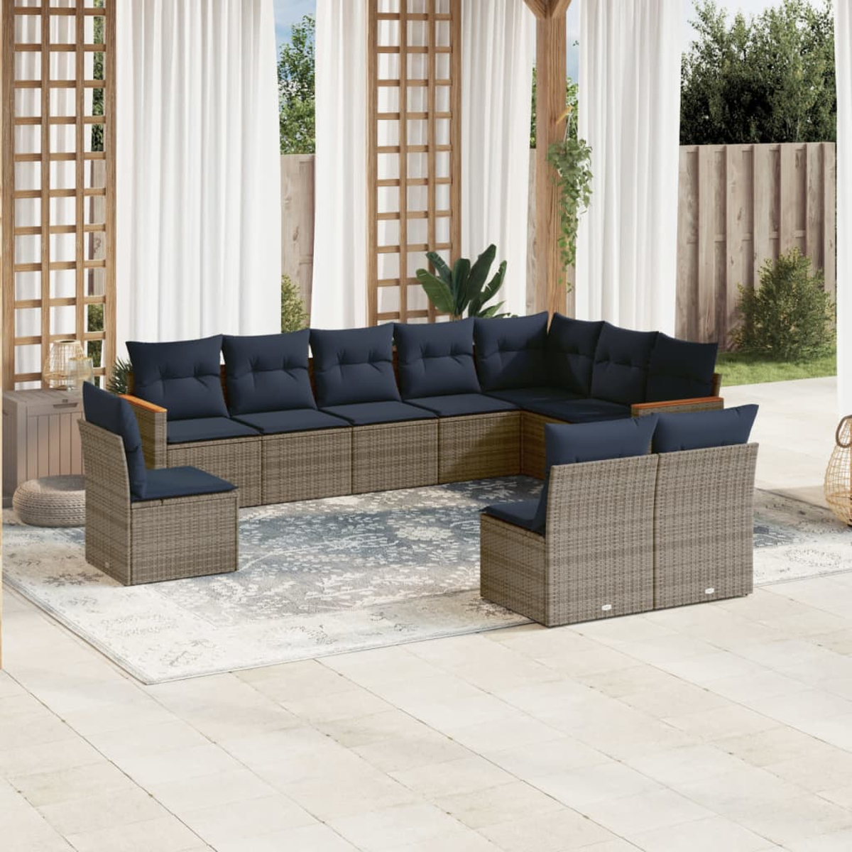 Outdoor-Ecksofa mit marineblauen Kissen. Es steht auf einem gemusterten Teppich. Weiße Vorhänge und Holzstrukturen bilden den Hintergrund.