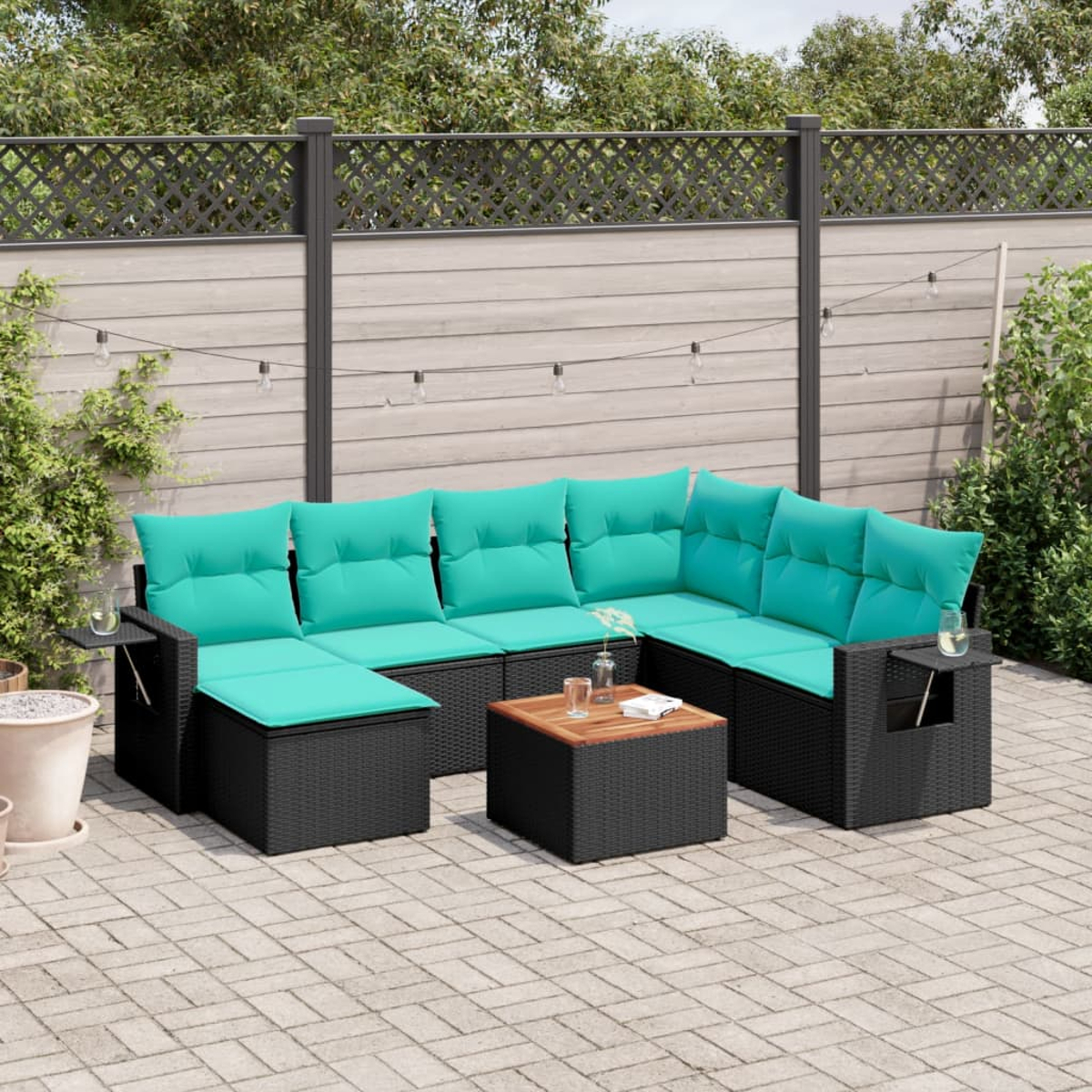 Ein Outdoor-Ecksofa mit türkisfarbenen Kissen und schwarzem Korbgewebe. Davor steht ein quadratischer Couchtisch aus Holz. Der Hintergrund umfasst einen Zaun.