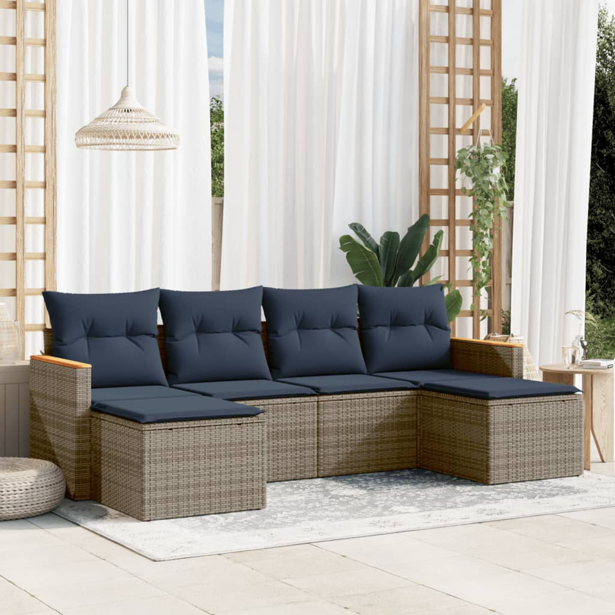 Outdoor-Ecksofa mit marineblauen Kissen auf einem grauen Teppich. Weiße Vorhänge und ein Holzspalier sind im Hintergrund, mit einer Hängelampe.