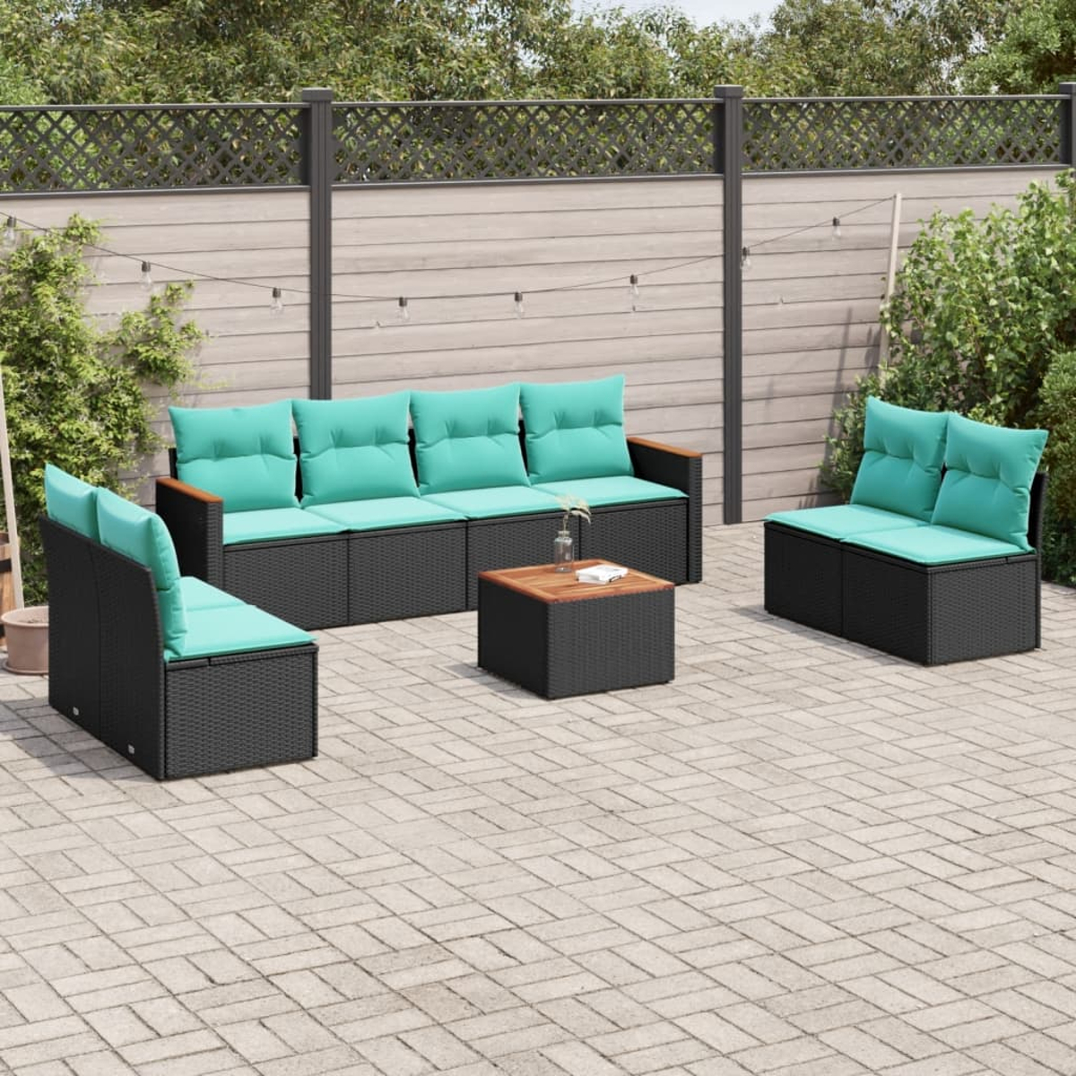 Un juego de muebles de exterior de mimbre negro con cojines turquesa está en un patio. Una mesa de madera está en el centro.