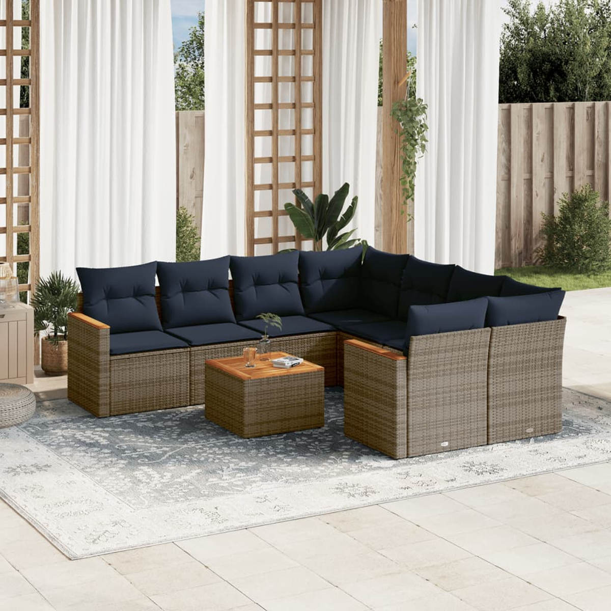 Outdoor-Ecksofa mit marineblauen Kissen und Couchtisch auf einem gemusterten Teppich. Weiße Vorhänge und Holzgitter im Hintergrund.