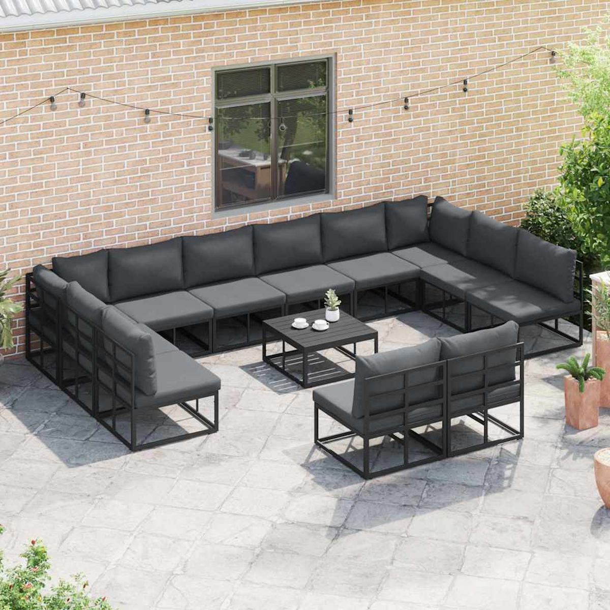 Gartenmöbel-Set. Dunkelgraue Kissen auf schwarzen Metallrahmen. Beinhaltet ein Ecksofa, zwei Stühle und einen Couchtisch.