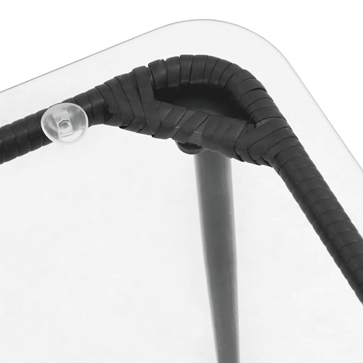 Nahaufnahme einer Glasecke mit schwarzem Webbesatz. Ein kleiner, klarer Gummistopfen ist sichtbar. Ein graues Metallbein ist ebenfalls vorhanden.