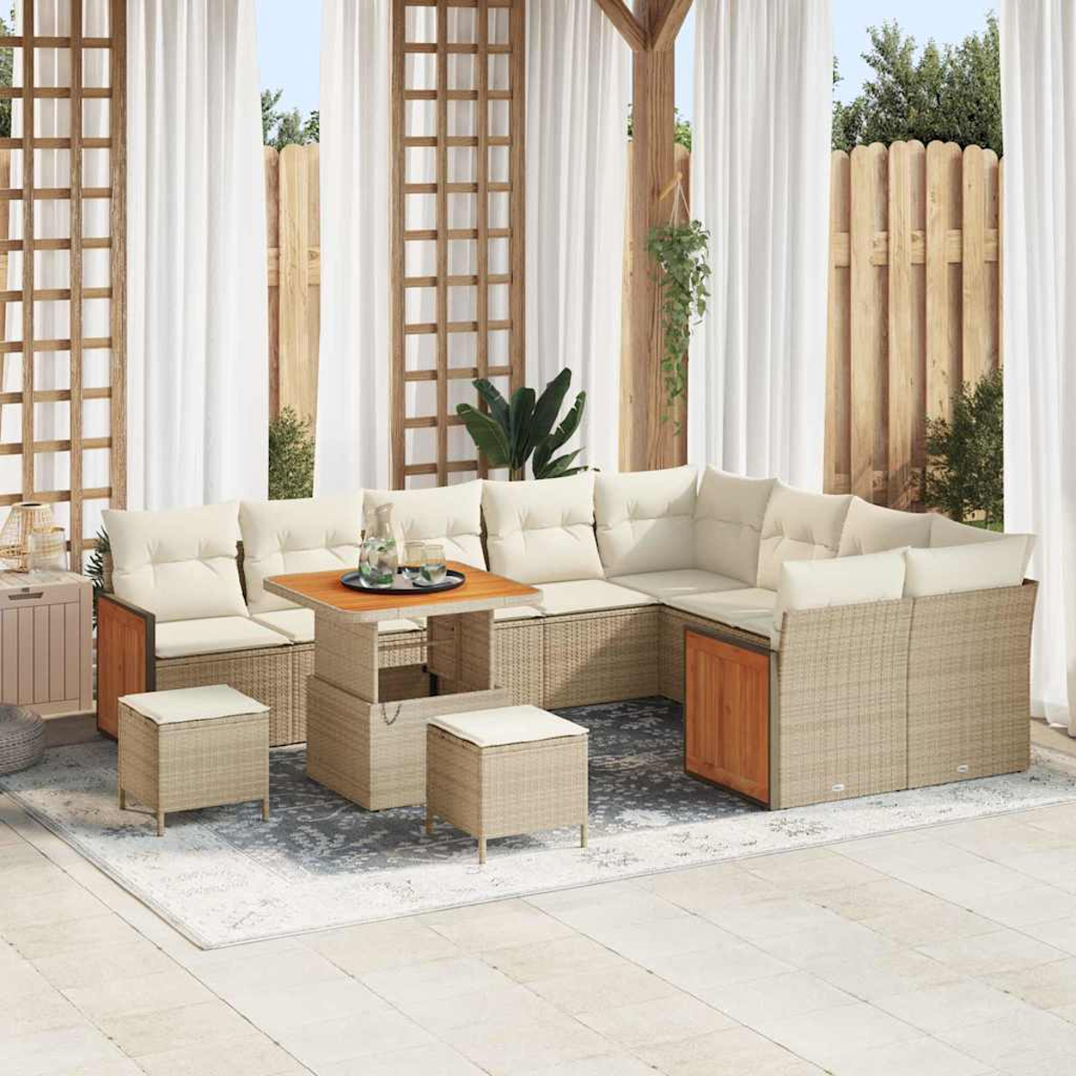 Outdoor-Sitzgruppe mit beigen Kissen. Enthält Ecksofa, Tisch und Ottomanen auf einem Teppich. Gardinen und Holzzaun im Hintergrund.