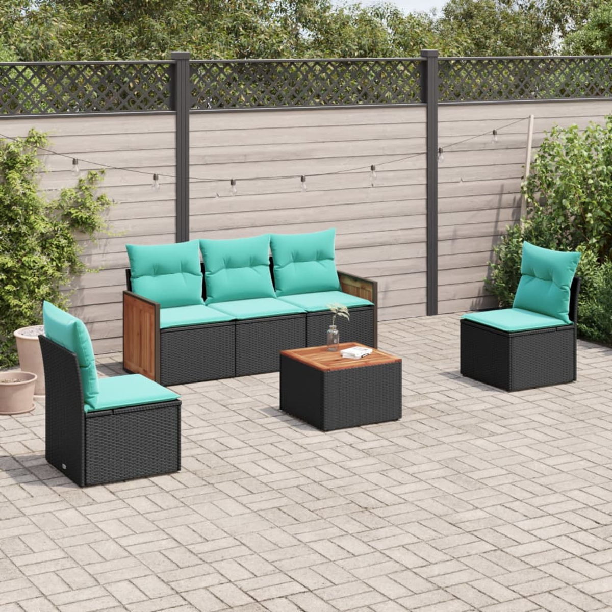 Juego de patio al aire libre con muebles de mimbre negro, cojines turquesa y mesa de café de madera en patio de piedra.