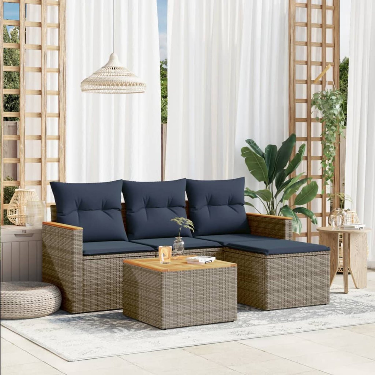 Juego de patio al aire libre con cojines azules, mesa de café de madera, cortinas blancas y una lámpara colgante. Plantas verdes al fondo.