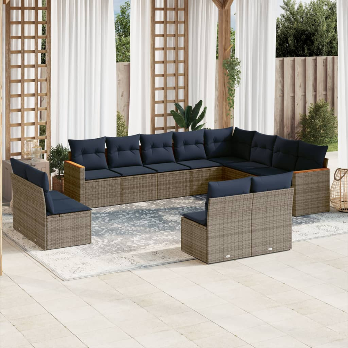 Sofá seccional al aire libre con cojines azul marino. Mimbre gris con detalles de madera. Incluye dos sillas y una alfombra en un patio.