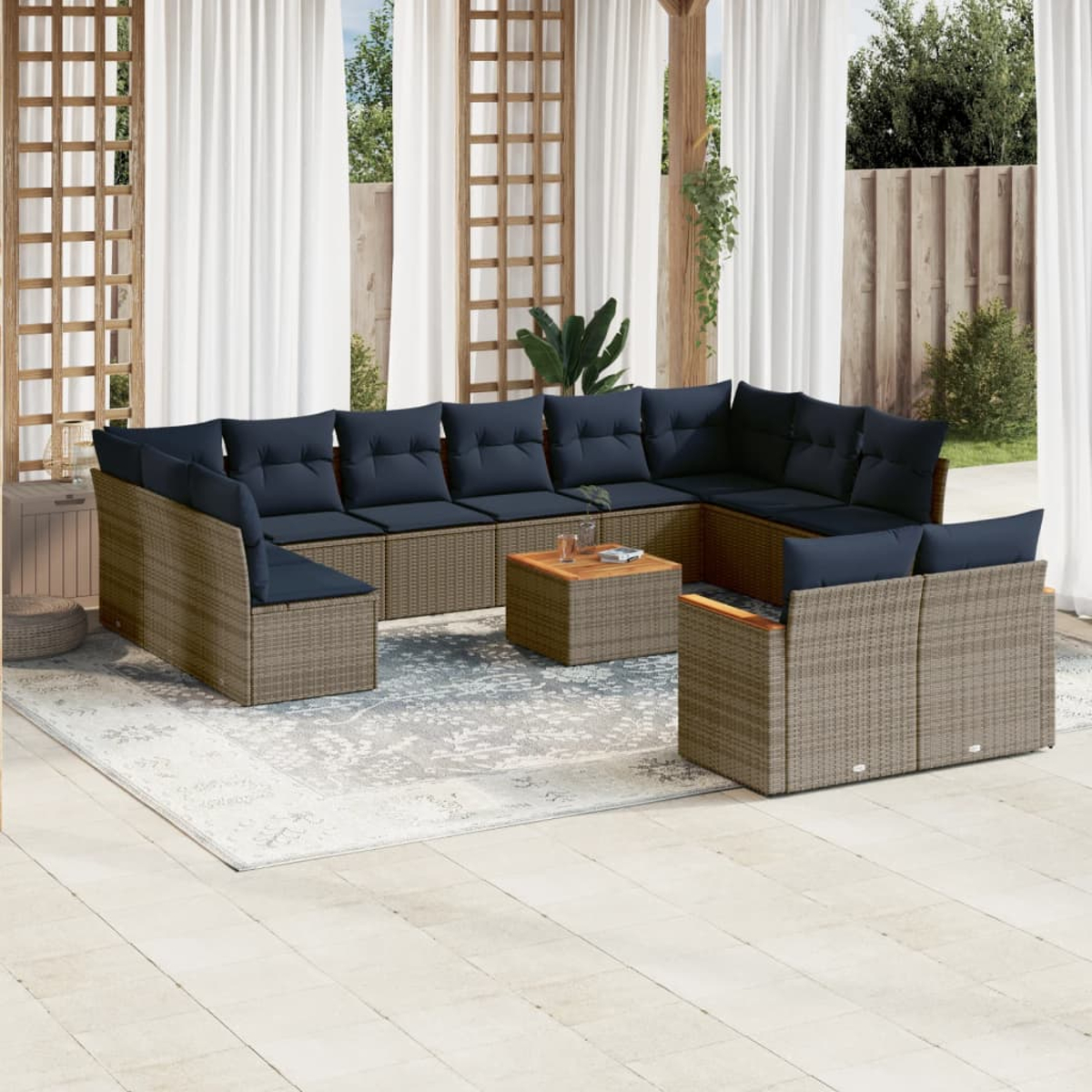 Outdoor-Ecksofa mit marineblauen Kissen und einem Couchtisch aus Holz auf einem gemusterten Teppich. Weiße Vorhänge und Holzgitter im Hintergrund.