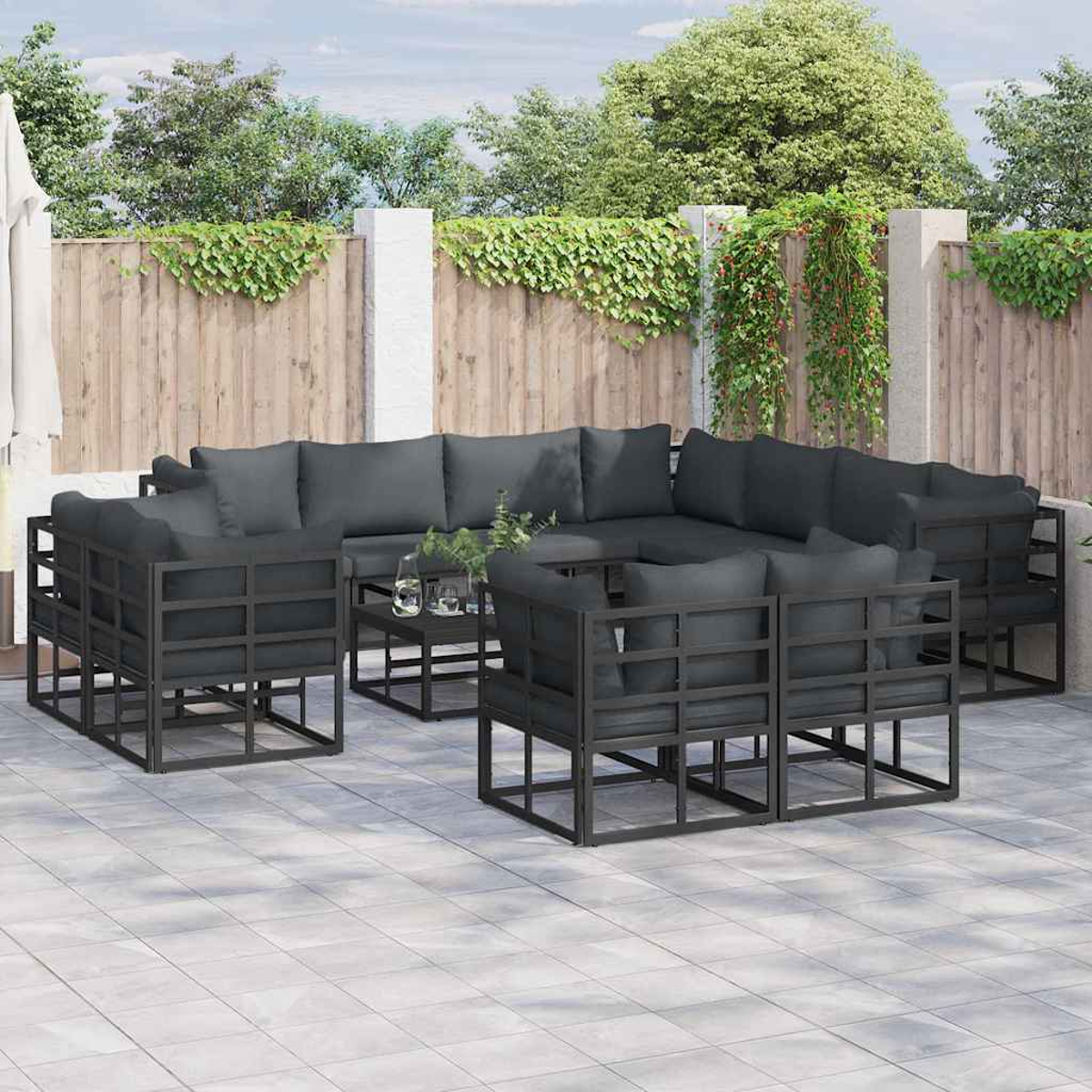 Gartenmöbel-Set mit dunkelgrauen Kissen und schwarzen Rahmen, angeordnet auf einer Terrasse. Enthält ein Ecksofa, Stühle und einen Tisch.