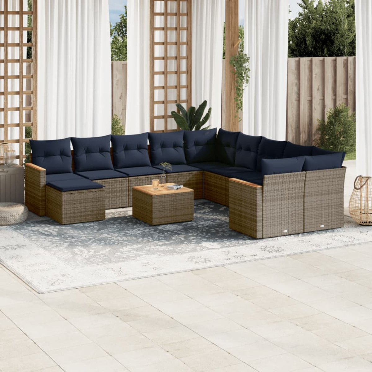 Sofá seccional para exteriores con cojines azules. Una mesita y una alfombra al frente. Cortinas blancas y valla de madera.