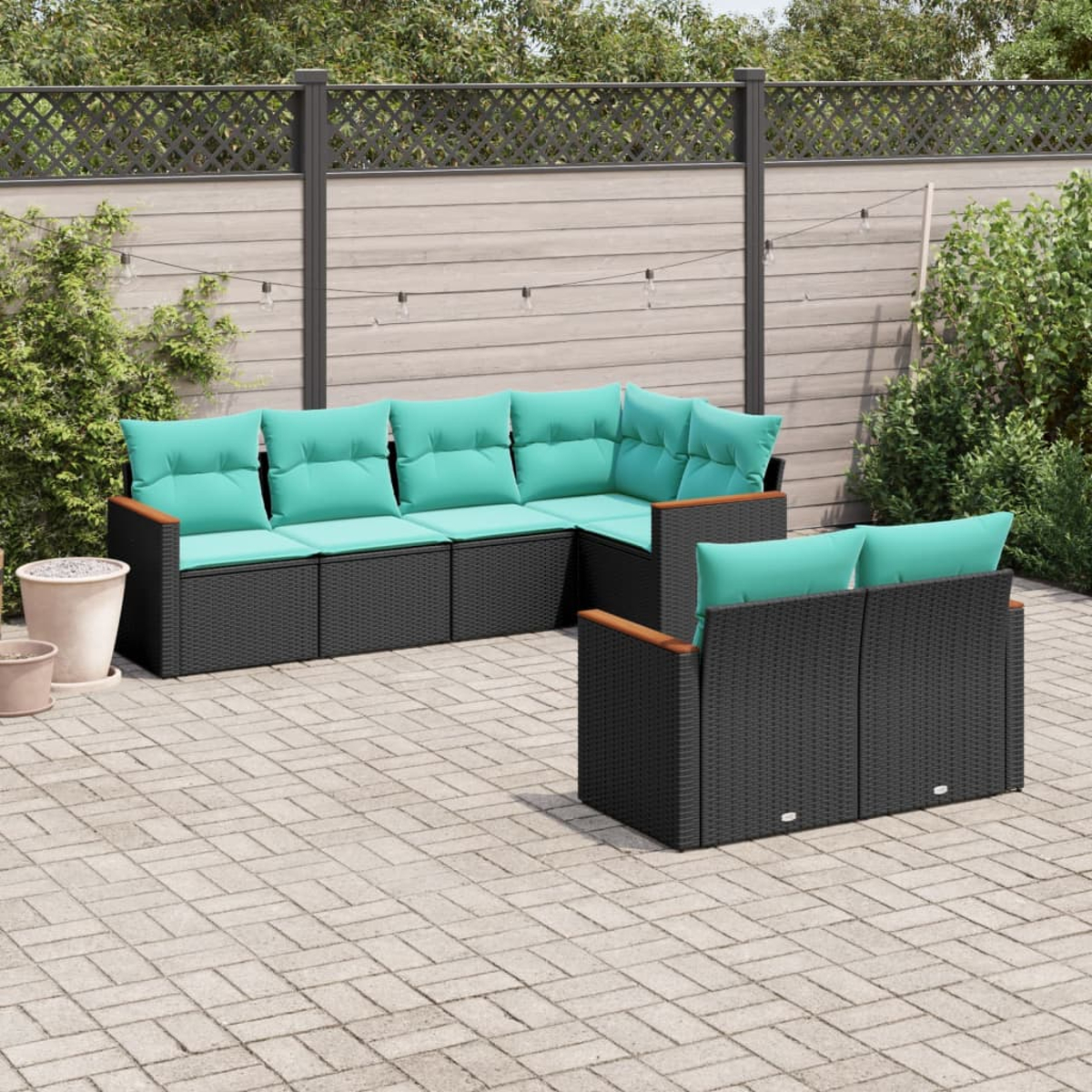 Juego de muebles de patio al aire libre con cojines turquesa. El juego está sobre un patio de ladrillos, rodeado de vegetación y una valla de madera.