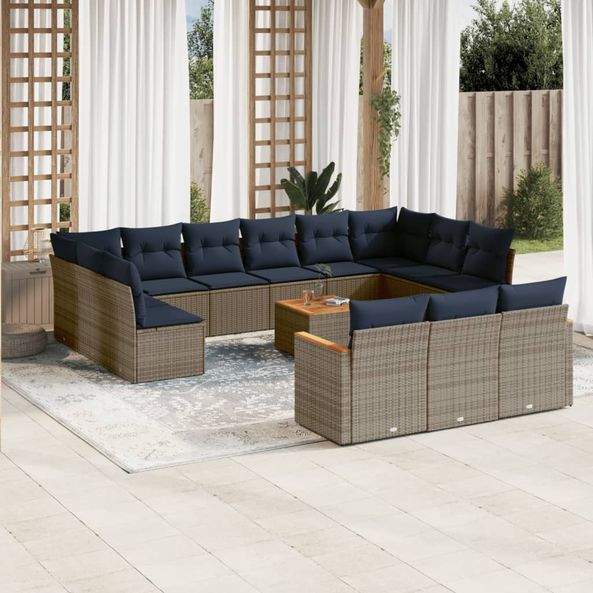 Outdoor-Ecksofa mit marineblauen Kissen, Couchtisch und Teppich auf einer Terrasse. Weiße Vorhänge und Holzgitter im Hintergrund.