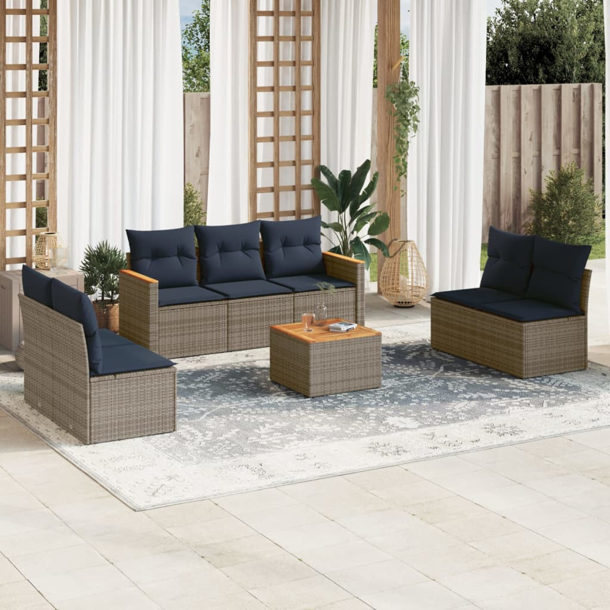 Terrassenset mit Sofa, zwei Stühlen und einem Couchtisch, alle mit blauen Kissen, auf einem gemusterten Teppich.
