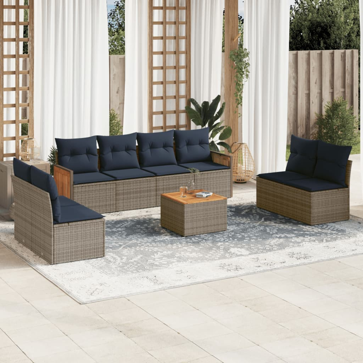 Juego de muebles de patio con sofá, dos sillas y una mesa de centro. Todos tienen cojines azul marino y están sobre una alfombra estampada.