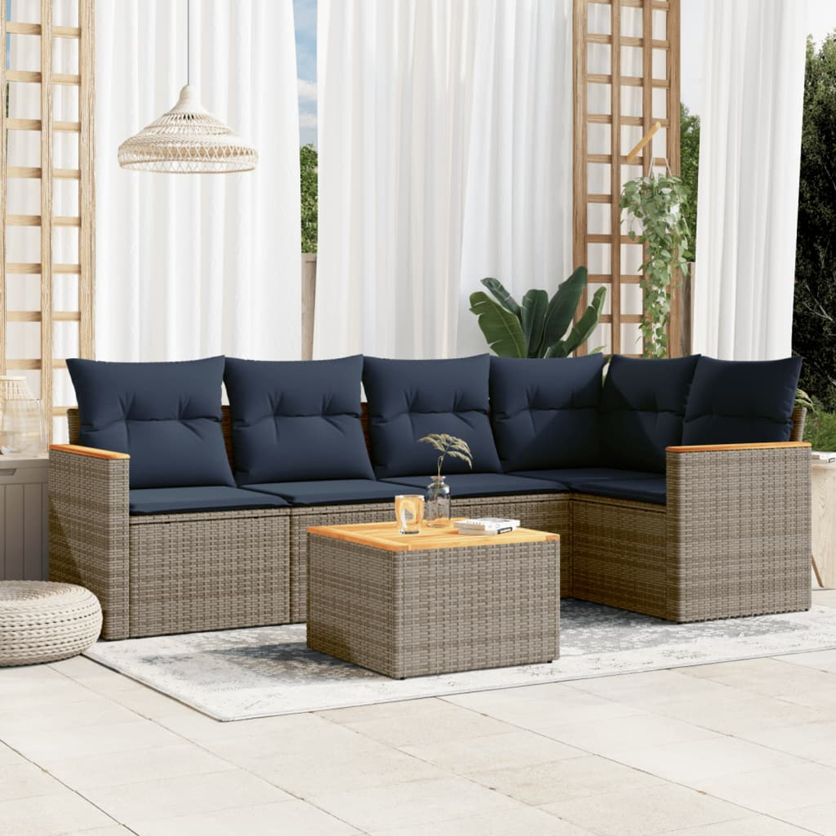 Outdoor-Ecksofa mit marineblauen Kissen und Holzakzenten. Ein passender Couchtisch steht auf einem Teppich. Weiße Vorhänge und eine Leuchte sind oben.