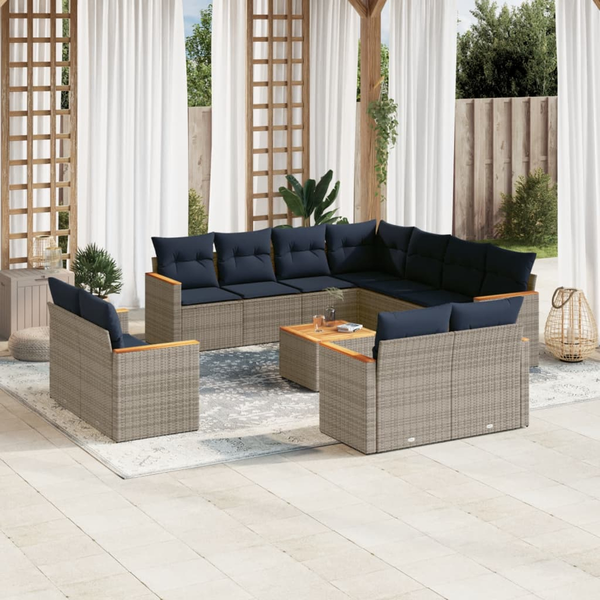 Gartenmöbel-Set: Ecksofa, zwei Sessel und ein Couchtisch. Alles hellbraunes Korbgeflecht mit blauen Kissen. Ein Teppich und Vorhänge sind im Hintergrund.