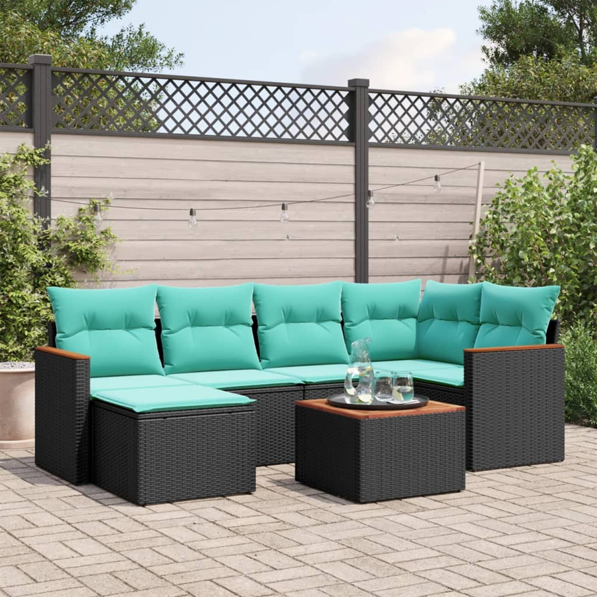 Outdoor-Ecksofa mit türkisfarbenen Kissen, schwarzem Korbgeflecht und Holzakzenten. In der Mitte steht ein kleiner Tisch mit Getränken.