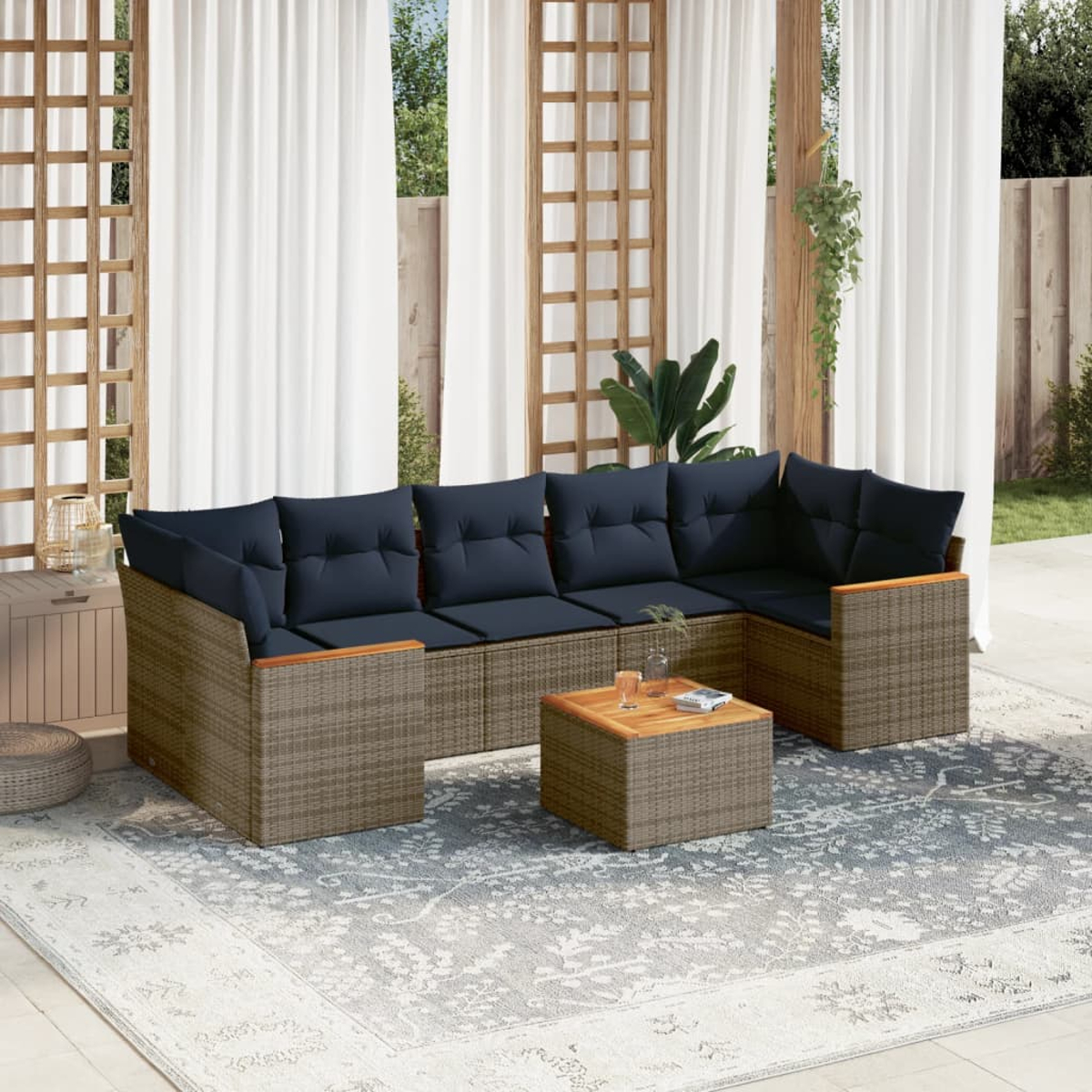 Outdoor-Ecksofa mit marineblauen Kissen, einem Holztisch und einem gemusterten Teppich. Weiße Vorhänge und ein Holzgitter im Hintergrund.