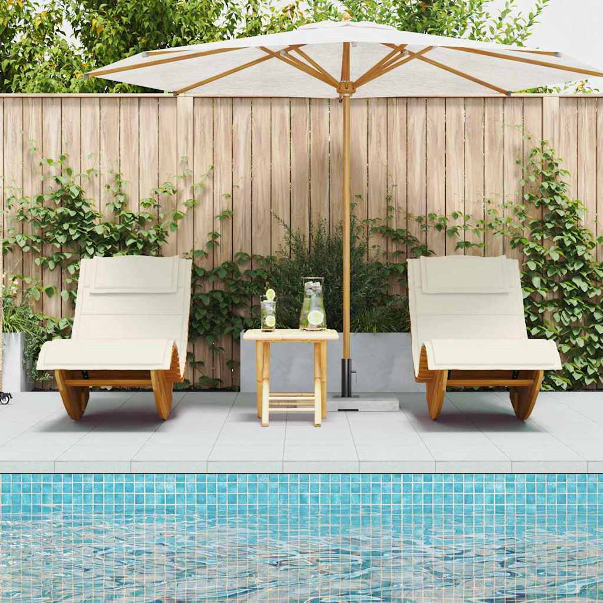 Zwei cremefarbene Liegestühle am Pool, mit einem kleinen Tisch dazwischen. Ein weißer Schirm spendet Schatten. Holzzaun im Hintergrund.