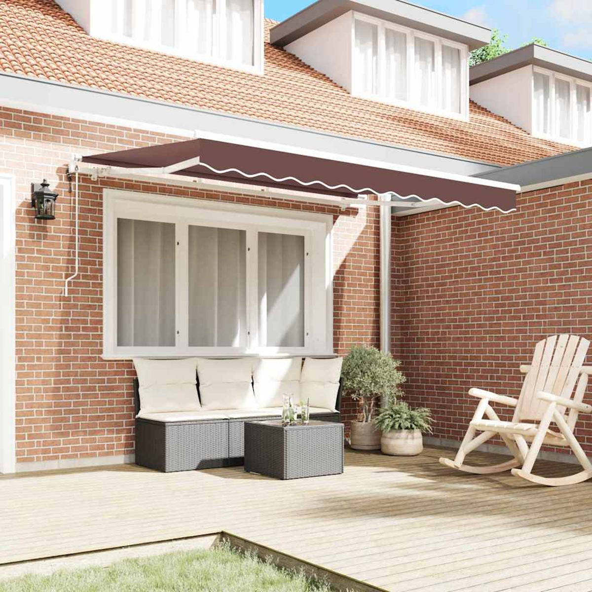 Eine braune Markise beschattet eine Terrasse mit Sofa, Tisch und Schaukelstuhl. Im Hintergrund ein Backsteinhaus mit Fenstern.