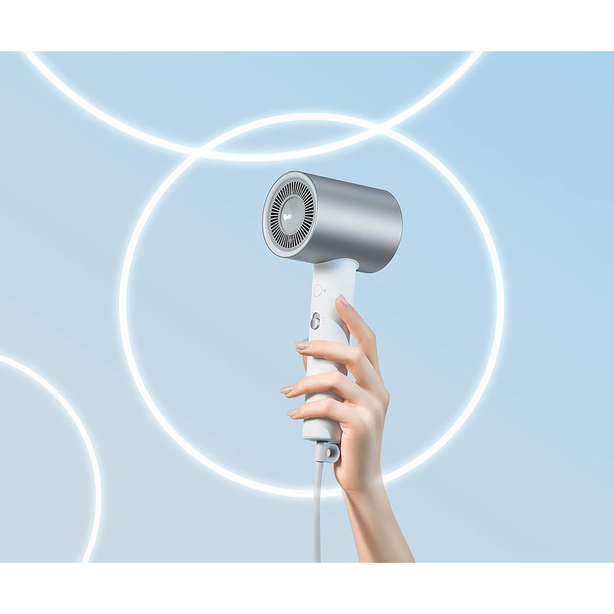 Dłoń trzyma srebrno-białą suszarkę do włosów. Tło jest jasnoniebieskie z białymi okrągłymi liniami.