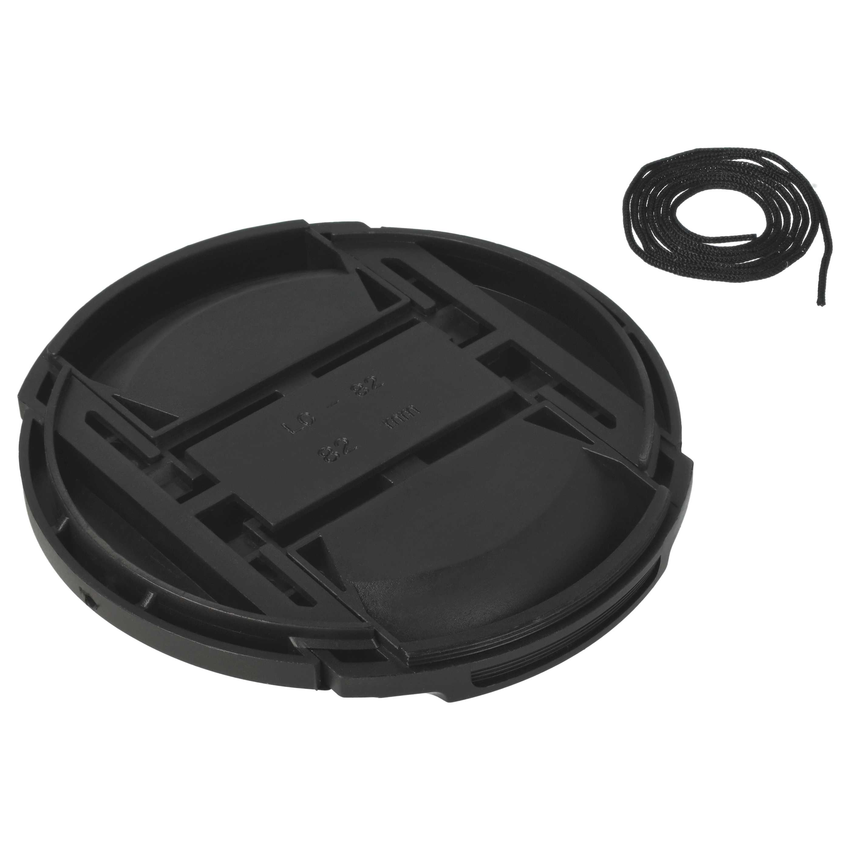 Eine schwarze Objektivkappe mit einer Schnur liegt auf weißem Hintergrund. Die Kappe ist rund mit strukturierter Oberfläche.