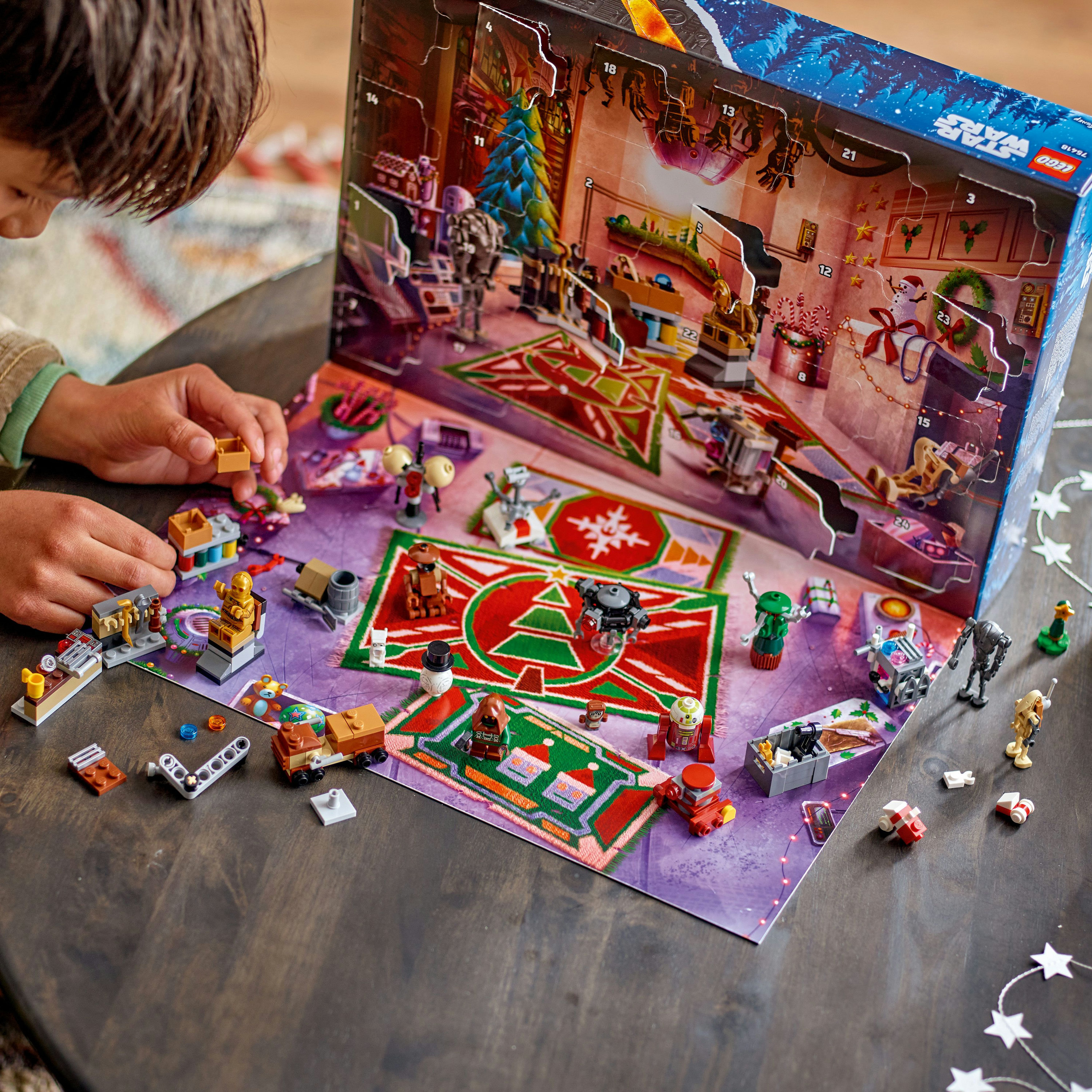 Dziecko bawi się figurkami Lego Star Wars. Kalendarz adwentowy o tematyce świątecznej w tle, na ciemnym drewnianym stole.