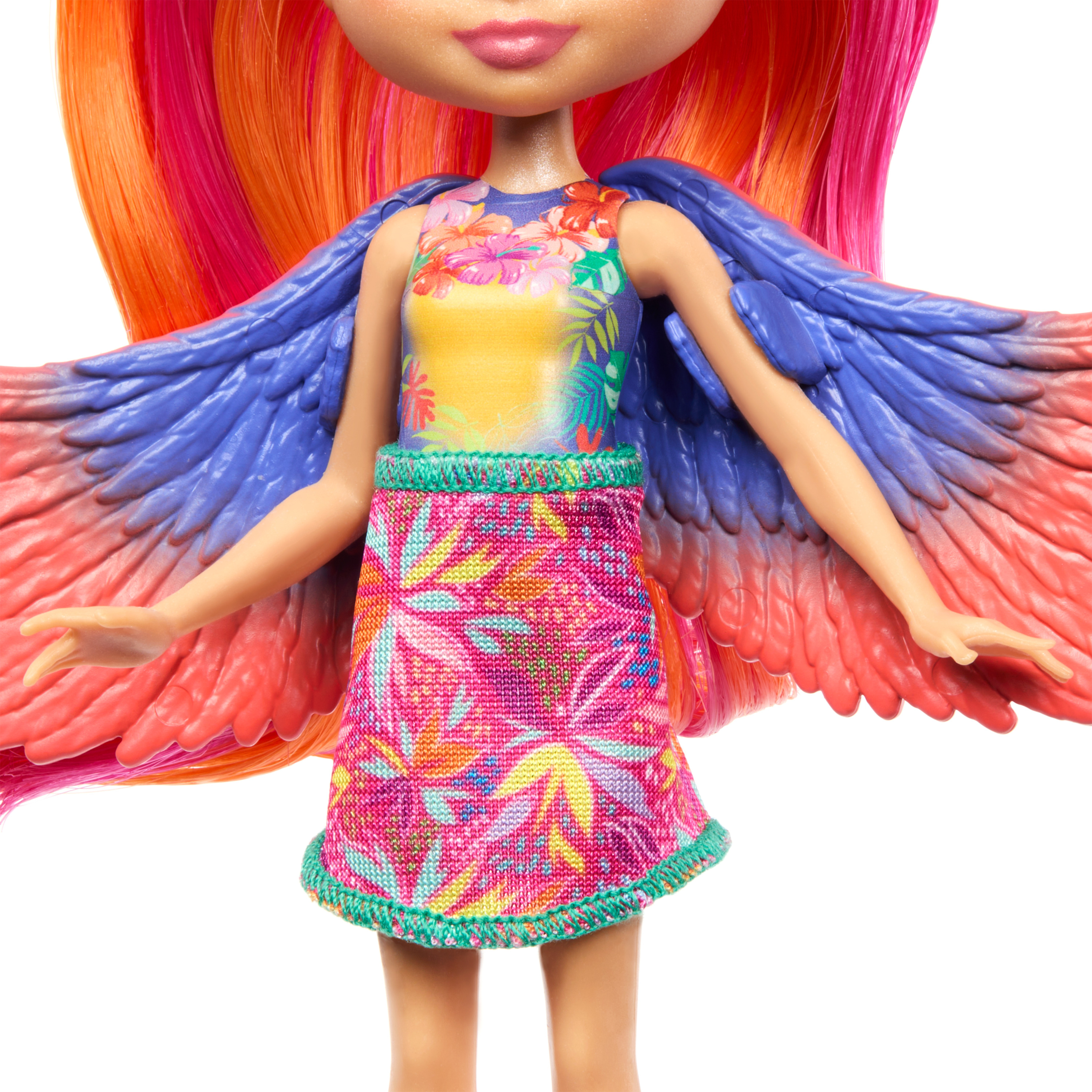 Una muñeca con pelo y alas coloridas. Lleva un top y una falda con flores. Las alas son azules y rojas.
