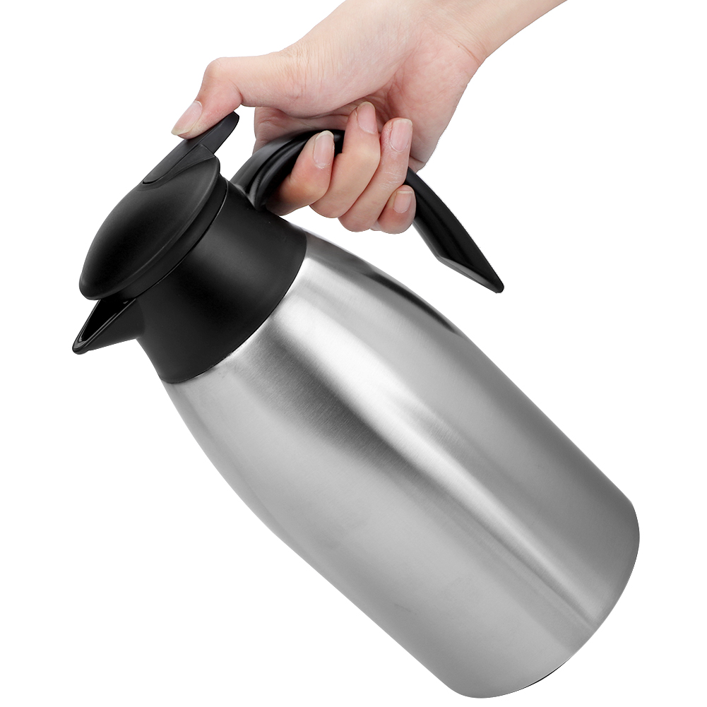 Eine Hand hält eine Edelstahl-Thermoskanne mit schwarzem Griff und Deckel. Der Hintergrund ist weiß.